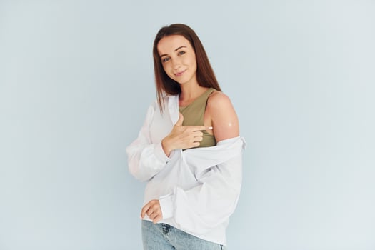 Successful vaccination. Young woman in white clothes sitting indoors against white background photo
