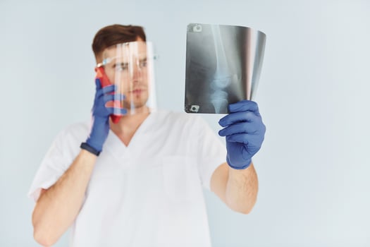 In white uniform. Young male doctor is indoors against white background photo