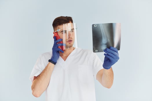 In white uniform. Young male doctor is indoors against white background photo