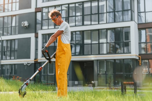 Busy day. Man cut the grass with lawn mover outdoors in the yard photo