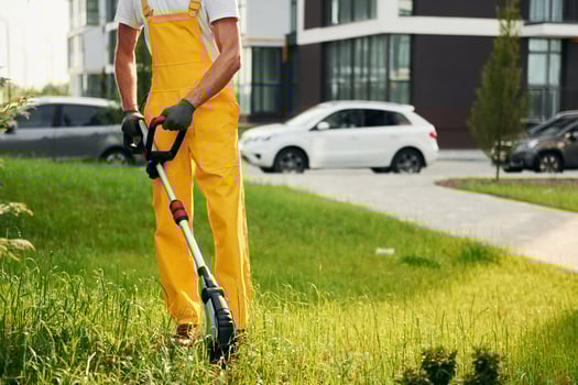 Building exterior at background. Man cut the grass with lawn mover outdoors in the yard photo