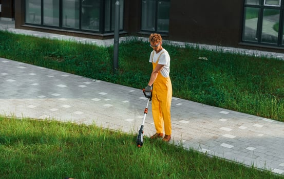 Distant view. Man cut the grass with lawn mover outdoors in the yard photo