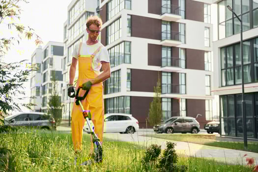 Modern buildings. Man cut the grass with lawn mover outdoors in the yard photo