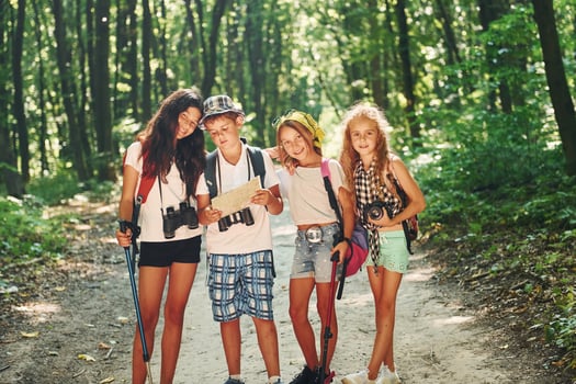 Front view. Kids strolling in the forest with travel equipment photo