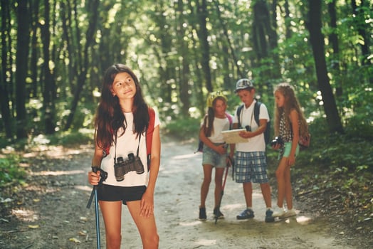 Front view. Kids strolling in the forest with travel equipment photo