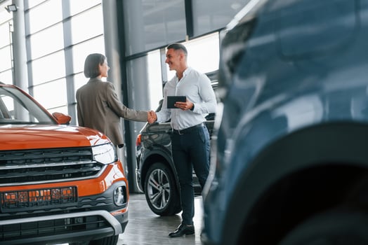 Making agreement. Man in formal wear helping customer with choice of the automobile photo