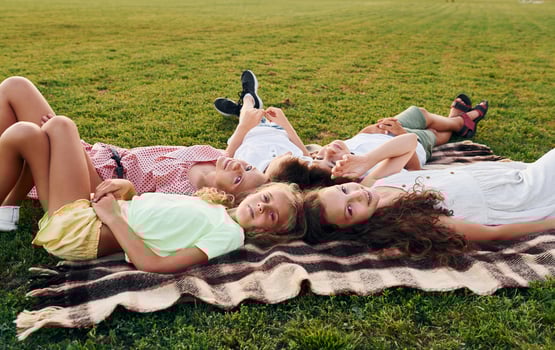 Having a rest and laying down. Group of happy kids is outdoors on the sportive field at daytime photo