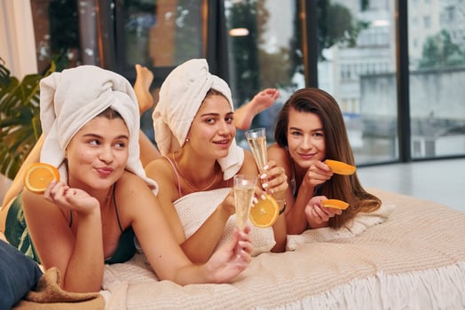 Laying down on bed with slices of orange. Group of happy women that is at a bachelorette party photo