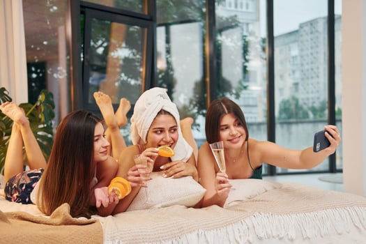 Laying down on bed with slices of orange. Group of happy women that is at a bachelorette party photo