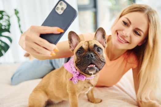 Doing selfie. Woman with pug dog is at home at daytime photo