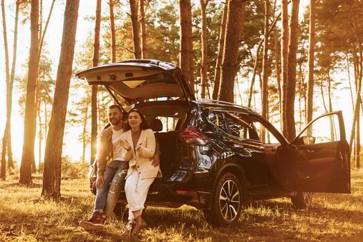 Happy couple standing outdoors in the forest with automobile photo