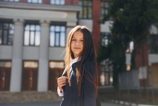 Schoolgirl is outside near school building photo