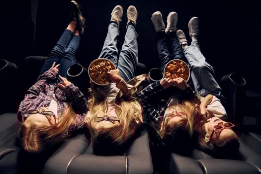 Delicious popcorn. Group of kids sitting in cinema and watching movie together photo