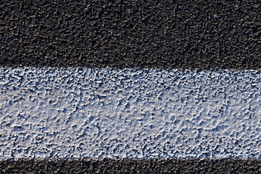 close up of an asphalt road with white road markings photo
