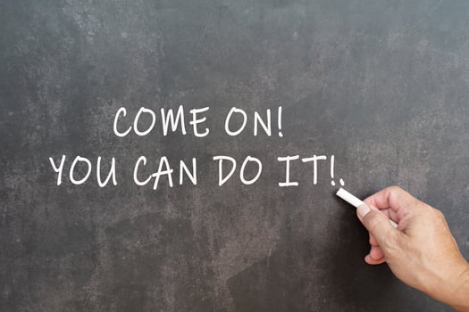 Male hand writes in white chalk pencil the word come on you can do it. photo