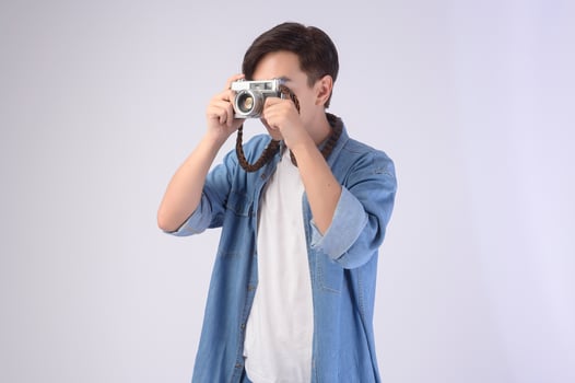 Young happy asian tourist man over white background studio, travel and holidays concept. photo