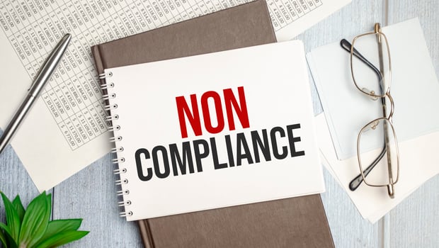 NON COMPLIANCE text on the paper with pen photo