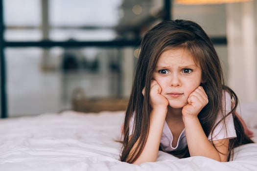 Cute little girl with a sad face lying on the bed photo