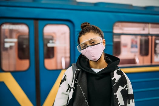 Young woman standing at station in medical protective mask photo