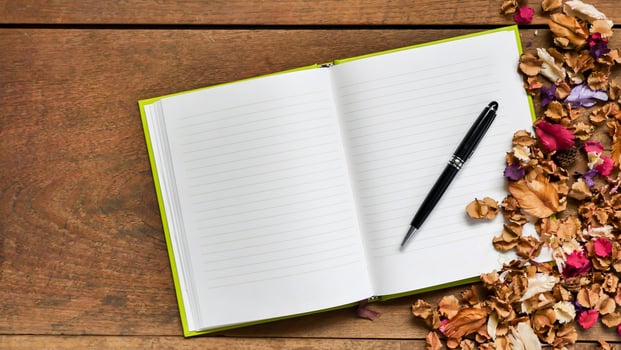 Top view workspace with blank notebook,pen and dried flowers on wooden table background . photo