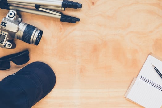 Top view of camera with tripod,hat,glasses and notebook on the wooden table background. photo
