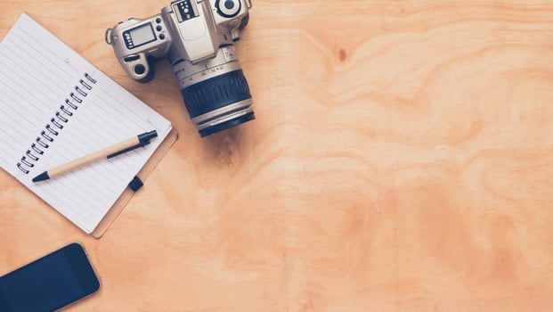 Top view of camera with notebook,pen and mobilephone on wooden table background. photo
