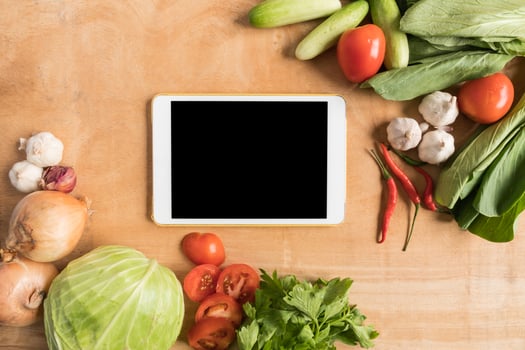 Top view of Fresh vegetables with tablet touch computer gadget on wooden table background. photo