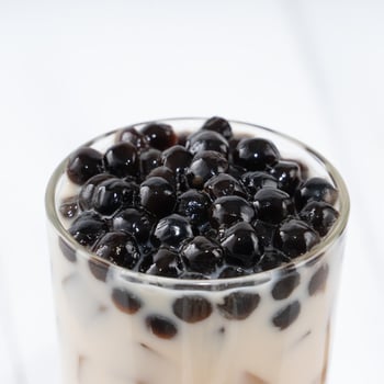 Bubble milk tea with tapioca pearl topping, famous Taiwanese drink on white wooden table background in drinking glass, close up, copy space photo