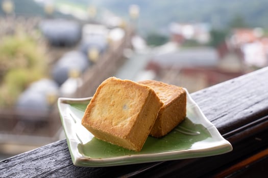 Delicious pineapple pastry in a plate for afternoon tea on wooden railing of a teahouse in Taiwan with beautiful landscape in background, close up. photo