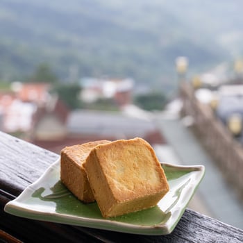 Delicious pineapple pastry in a plate for afternoon tea on wooden railing of a teahouse in Taiwan with beautiful landscape in background, close up. photo