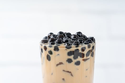 Bubble milk tea with tapioca pearl topping, famous Taiwanese drink on white wooden table background in drinking glass, close up, copy space photo