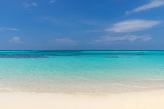 Closeup of sand on beach and blue summer sky. Panoramic beach landscape. Empty tropical beach and seascape. Pastel colored blue sunny sky, soft sand, calmness, tranquil relaxing sunlight, summer mood photo