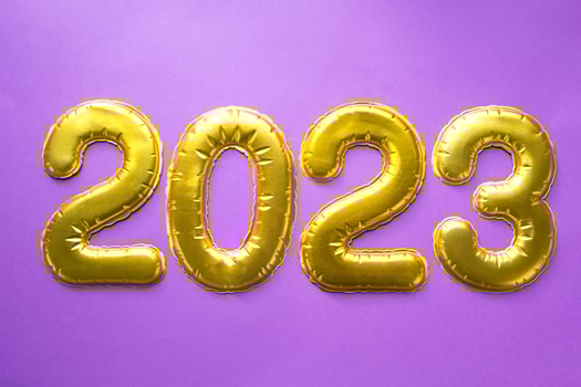 Happy New Year- golden numbers 2023 on a purple background with sequins, stars, glitter, lights of garlands. Greetings, postcard. Calendar, cover. photo