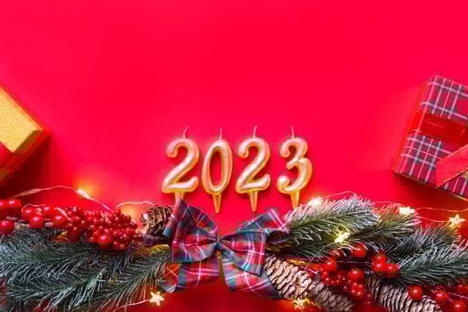 Happy New Year- golden candles numbers 2023 on a red background with Christmas tree, sequins, stars, glitter, gift boxes. Greetings, postcard. Calendar, cover. photo