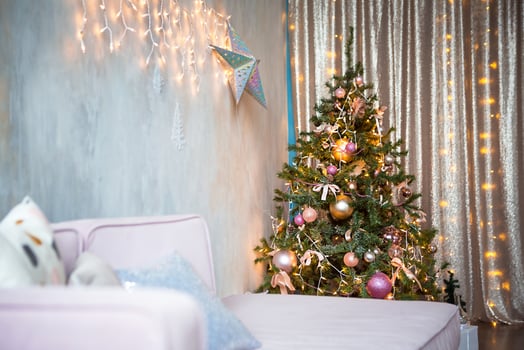 Decorated Christmas tree in the living room with sofa, blanket, lights garlands. Bedroom with a bed. New year, Christmas photo