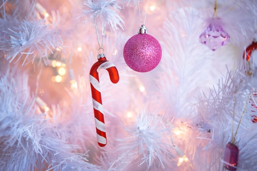 Christmas decorations on a white artificial Christmas tree a pink balloon and Santa's candy-striped cane. New year, festive background. space for text photo