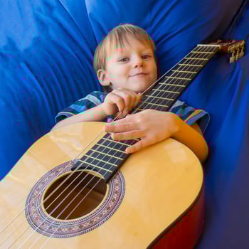 little boy plays guitar and sings on the balcony photo