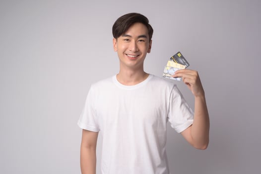 Young asian man holding credit card over white background studio, shopping and finance concept. photo
