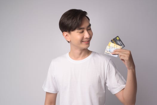 Young asian man holding credit card over white background studio, shopping and finance concept. photo