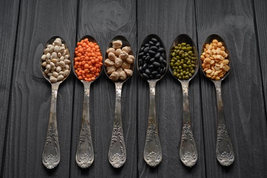 Variety of legumes in old silver spoons on a black wooden background. photo