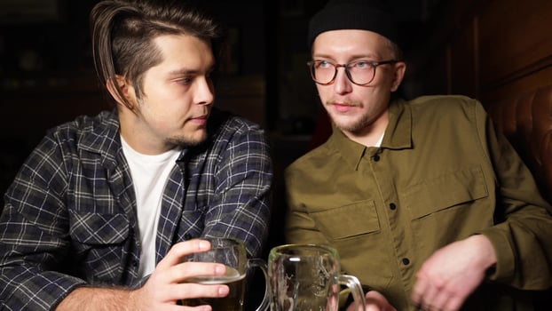 Young friends having fun together drinking beer and clinking glasses in a pub. photo