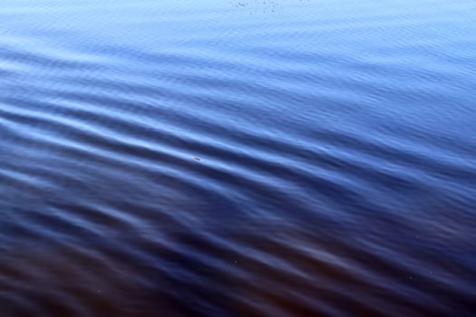 Detailed close up view on water surfaces with ripples and waves and the sunlight reflecting at the surface photo