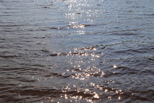 Detailed close up view on water surfaces with ripples and waves and the sunlight reflecting at the surface photo