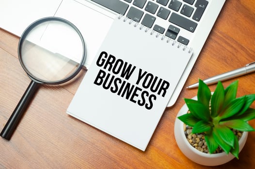 GROW YOUR BUSINESS writing text post it paper in office on laptop computer keyboard photo