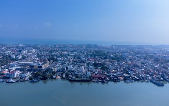 Fishing boats in a fishing village reflecting on the water. Life of a fishing village in shore of Songkhla, Thailand from drone bird eye view. photo