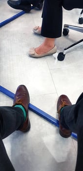 Leg of businessman and woman under table with white floor or tile background. Bottom view of brown and cream leather shoes with black pants. photo