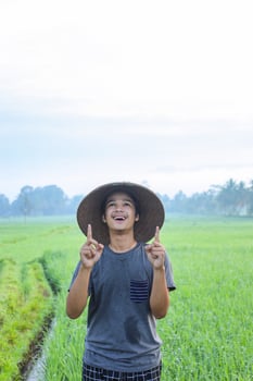 Portrait of attractive cheerful young Asian farmer standing and showing aha moment getting idea the rice field. Modern agriculture concept. photo
