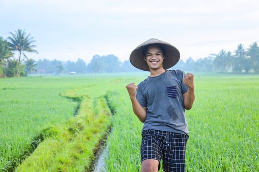 Close-up of attractive cheerful young Asian farmer rejoicing having success attainment to growing paddy rice at the rice field. Modern agriculture concept. photo