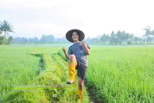 Attractive cheerful young Asian farmer rejoicing having success attainment to growing paddy rice at  the rice field. Modern agriculture concept. photo