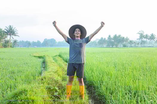 Young Asian millenial farmer standing and smile with feels proud of the success to growing paddy rice at  the rice field. Modern agriculture concept. photo